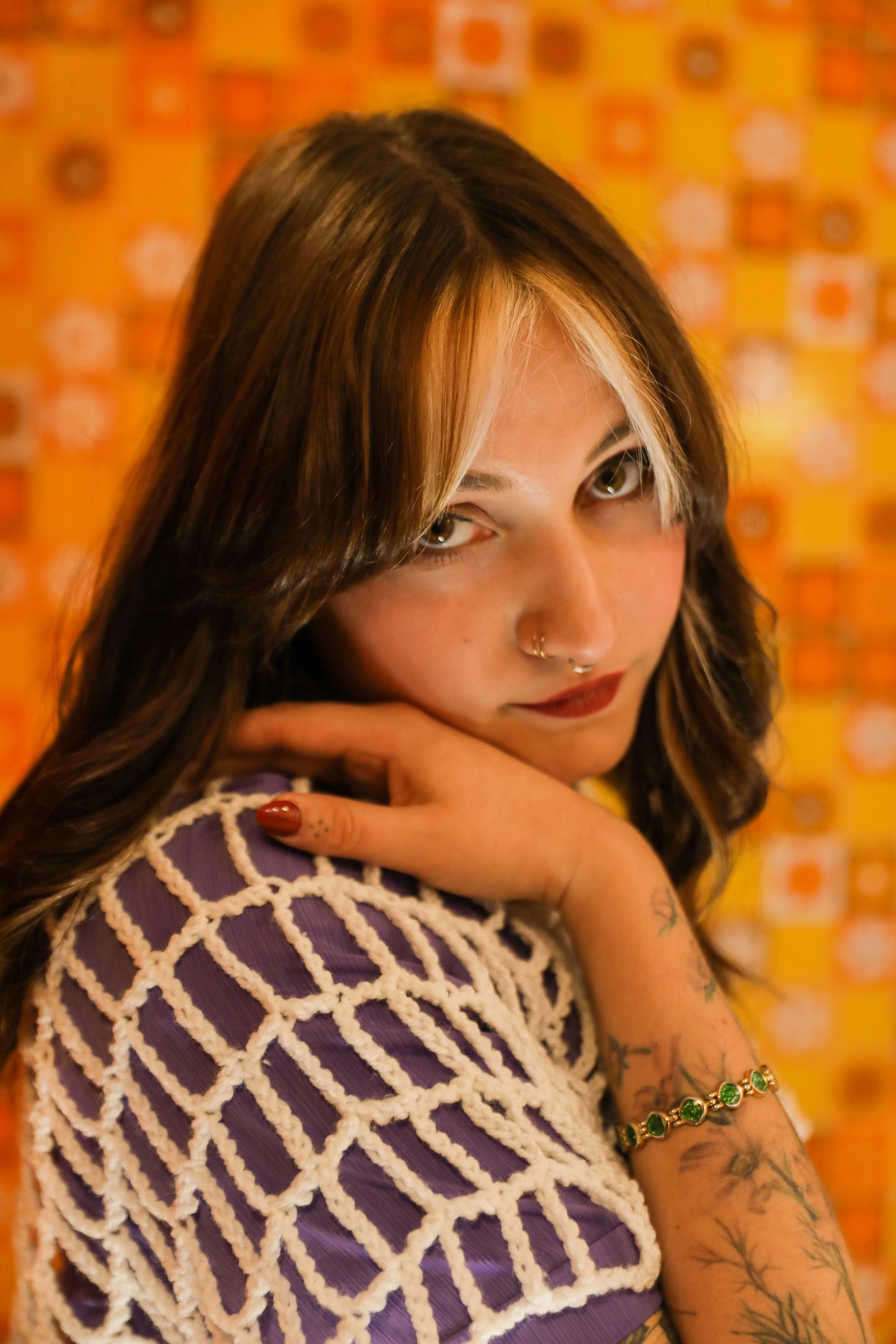 Portrait doux et attentif dans un univers orange des année 80 avec un croptop blanc de la série "OPEN" courte.frange ; une main visible posée sur son épaule qui maintient son visage.
Une création au crochet unique qui raconte la douceur, la tendresse et la nostalgie de notre enfance. 
Photographie en collaboration avec La Fripothèque (friperie :sélection de vêtements du magasin pour le shooting)